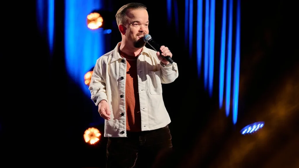 Brad Williams performing stand-up comedy on stage with microphone